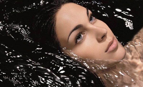 Woman's face in water with black background.